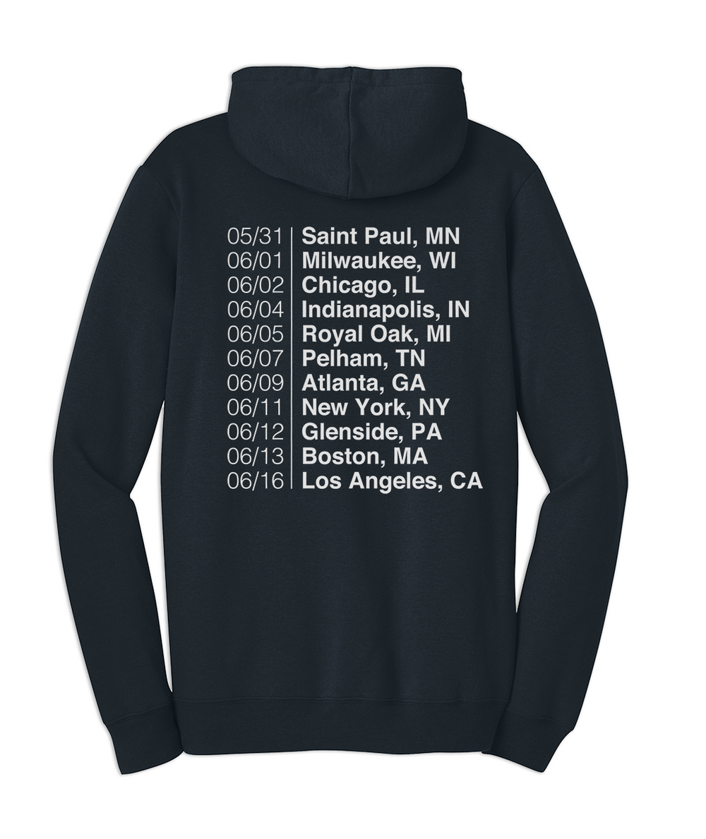 Back of the blue navy sweatshirt with The Areas Tour dates printed in white in the center back of the sweatshirt. "05/31 | Saint Paul, MN, 06/01 | Milwaukee, WI, 06/02 | Chicago, IL, 06/04 | Indianapolis, IN, 06/05 | Royal Oak, MI, 06/07 | Pelham, TN, 06/09 | Atlanta, GA, 06/11 | New York, NY, 06/12 | Glenside, PA, 06/13 | Boston, MA, 06/16 | Los Angeles, CA."